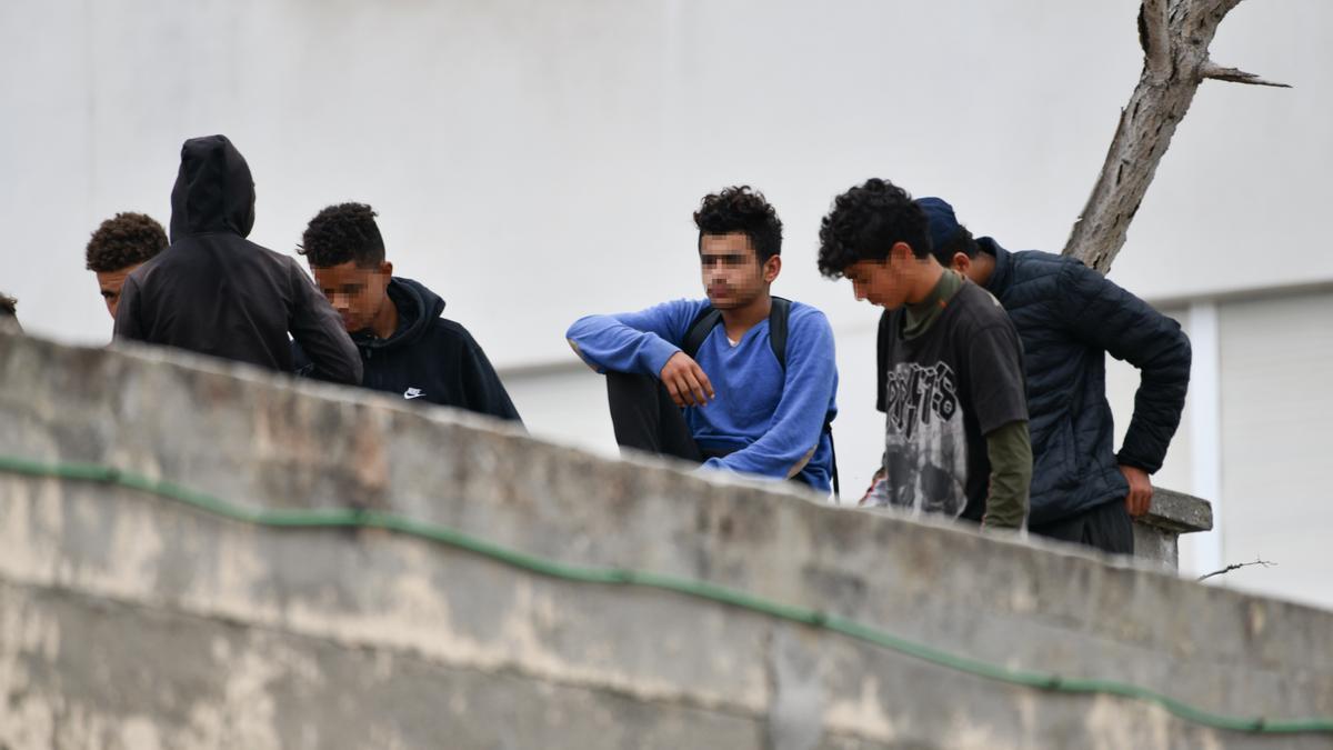 Varios menores migrantes, en el tejado de una nave industrial de Ceuta.