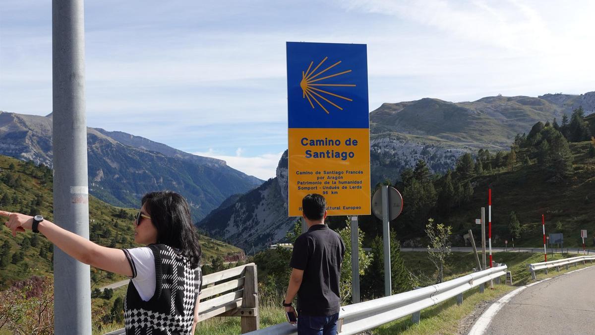 Dos turistas frente a uno de los carteles identificativos del Camino de Santiago aragonés.