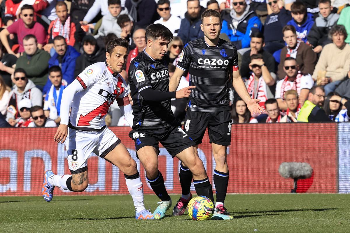 MADRID, 21/01/2023.- El centrocampista de la Real Sociedad Pablo Marín (c) con el balón perseguido por el centrocampista del Rayo Óscar Trejo (i) durante el partido de jornada 18 de LaLiga disputado este sábado en el Estadio de Vallecas. EFE/Zipi