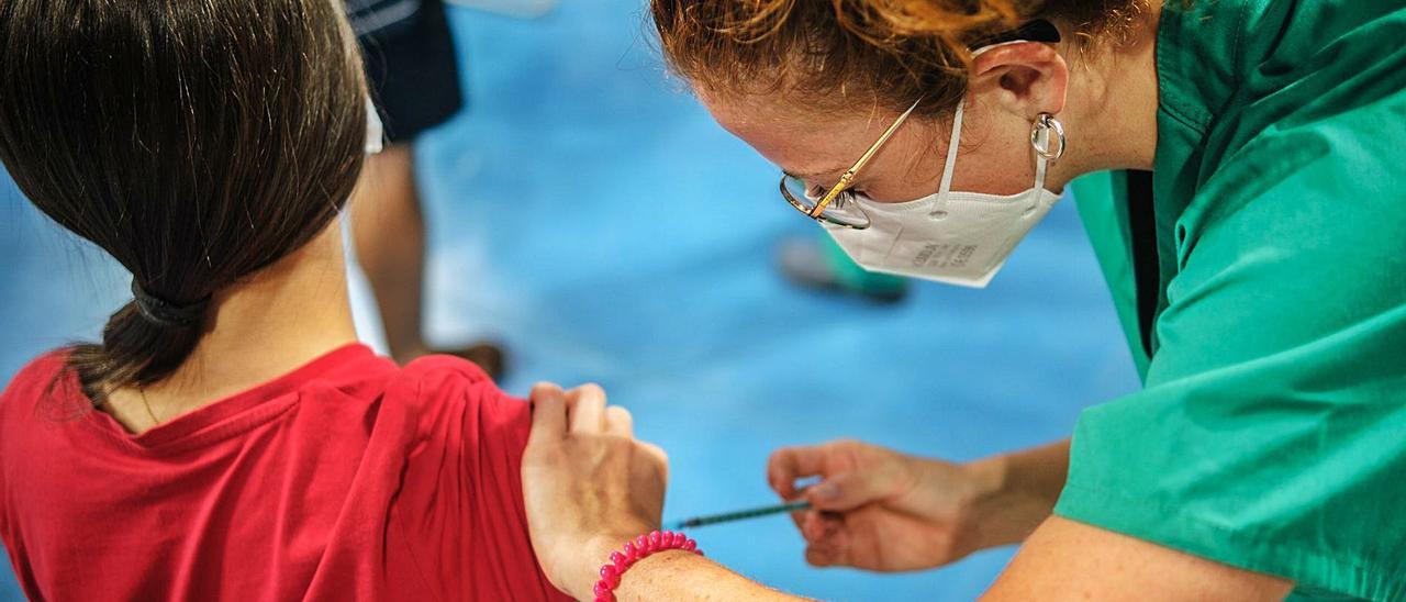 Una enfermera del Servicio Canario de la Salud vacuna a una joven en el vacunódromo del Pabellón Santiago Martín en Tenerife | | ANDRÉS GUTIÉRREZ