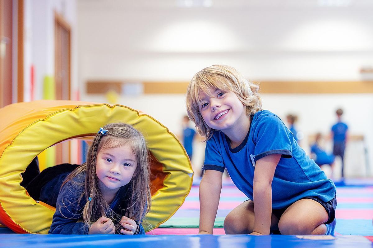 Dos pequeños posan sonrientes en un aula de gimnasia.