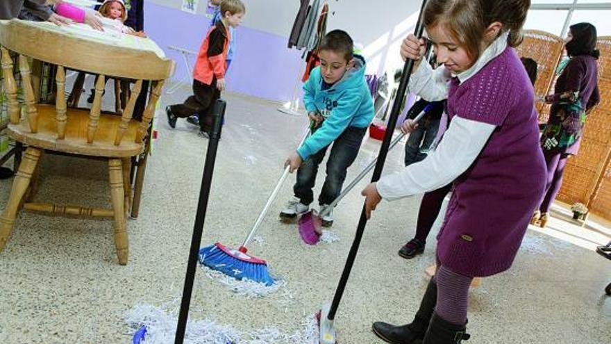 Un grupo de niños se esmera con la escoba y el recogedor.