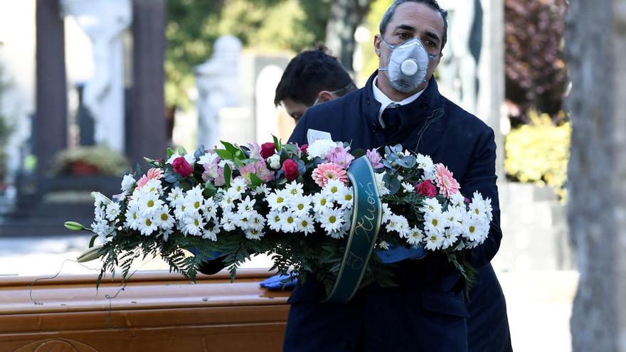 Trajadores funerarios con mascarilla en el cementerio de Bérgamo, saturado por el coronavirus.