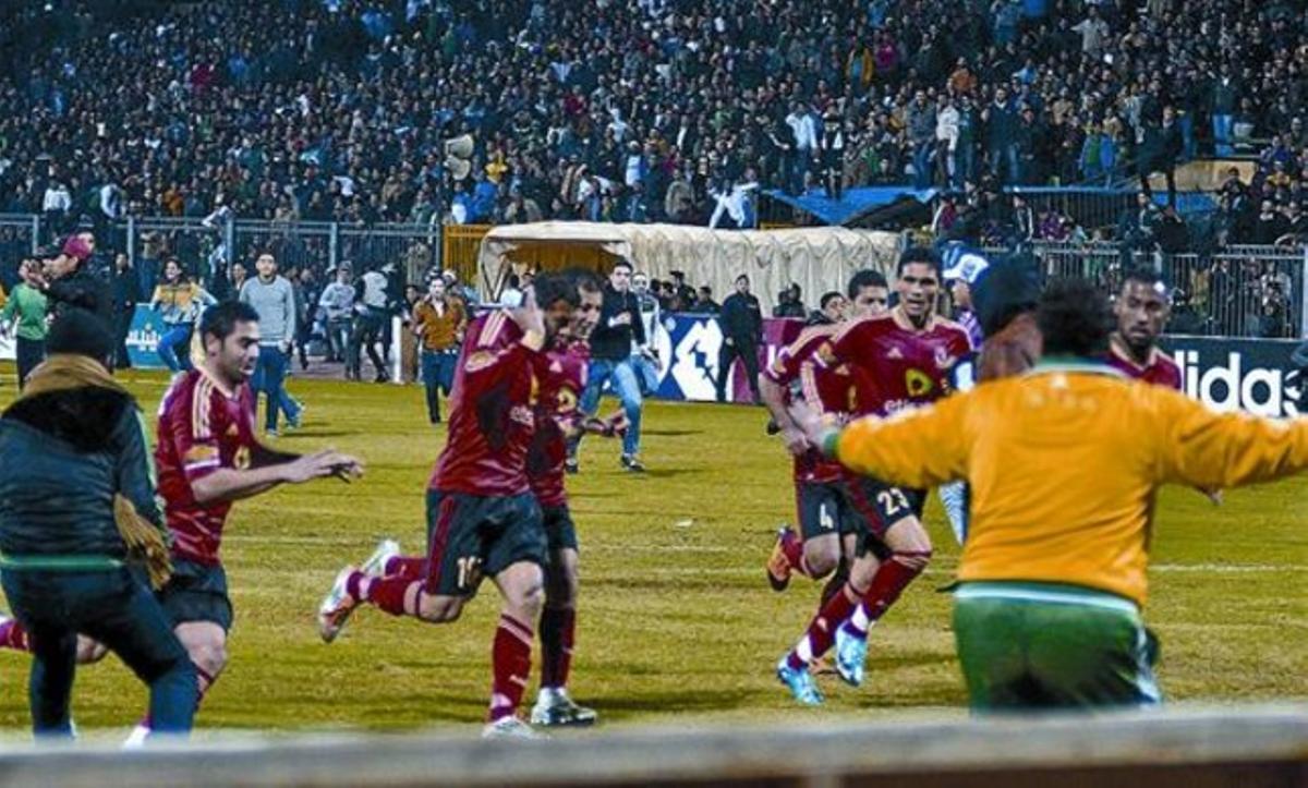 Los jugadores cairotas corren hacia los vestuarios al final del partido, perseguidos por los hinchas locales.