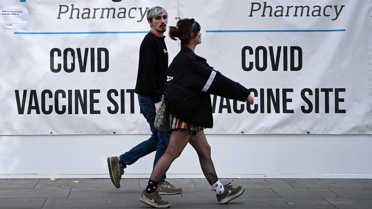 Dos jóvenes pasan junto a un centro de vacunación en Londres.
