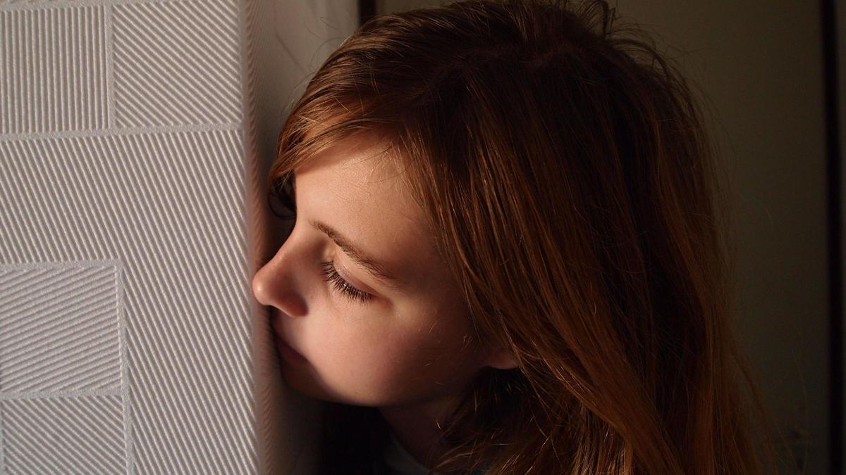 Una niña, asomándose a una puerta