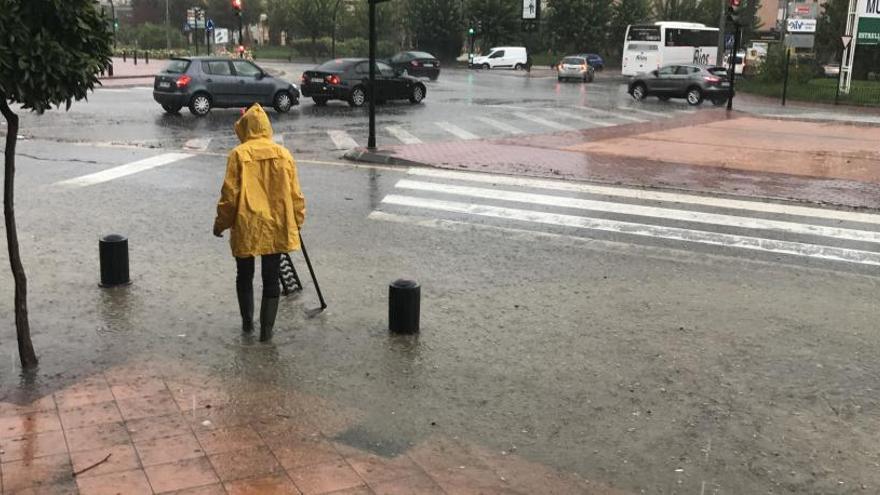 Un hombre, con chubasquero y botas de agua, en Plaza Castilla.