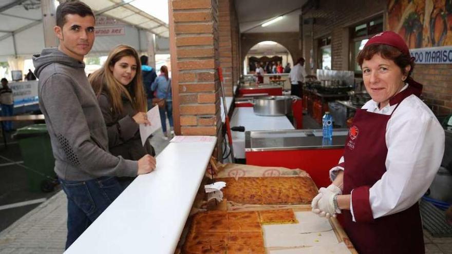 Dos de los comensales más madrugadores ante los soportales donde se instalan las cocinas. // Muñiz