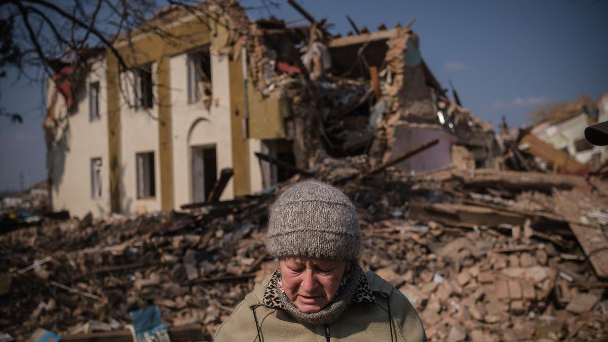Una mujer busca libros entre los escombros de la casa de la cultura de Byshiv.