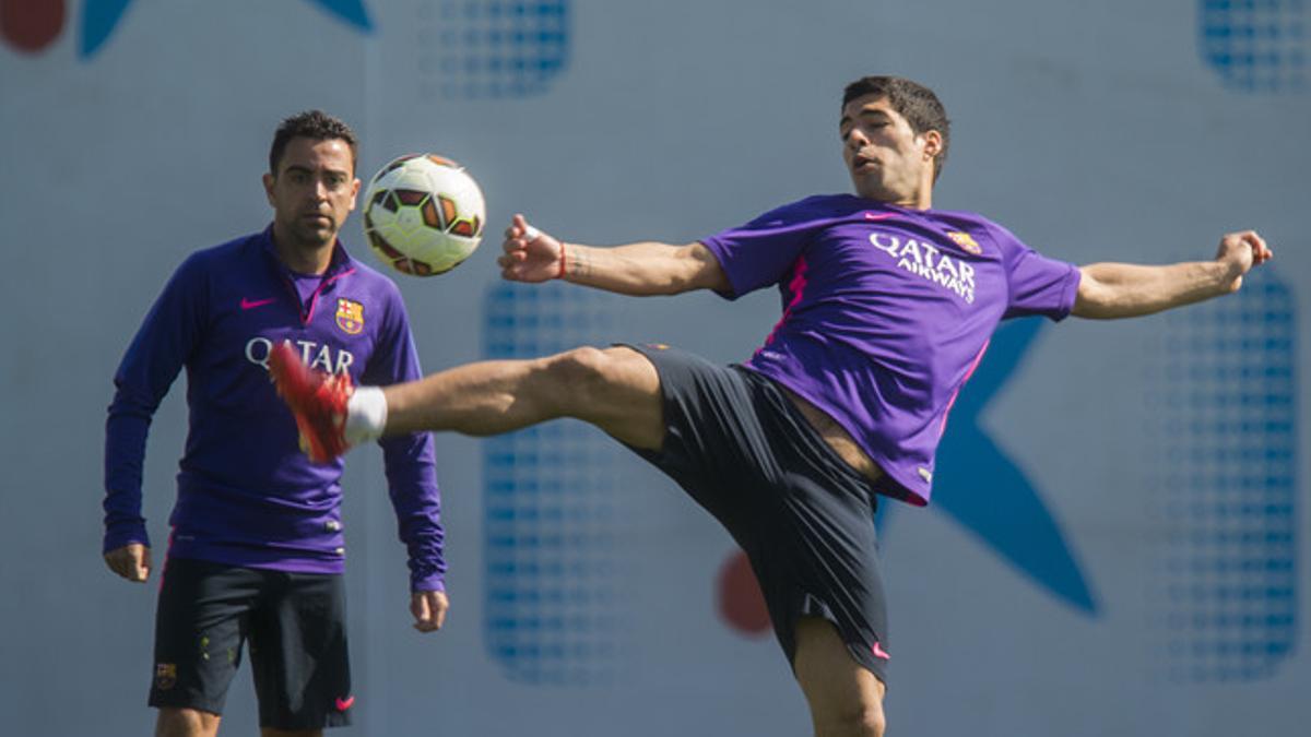 Fotografía de archivo. Luis Suarez trata de controlar el balón en presencia de Xavi durante una sesión del FC Barcelona en la 'ciutat esportiva'