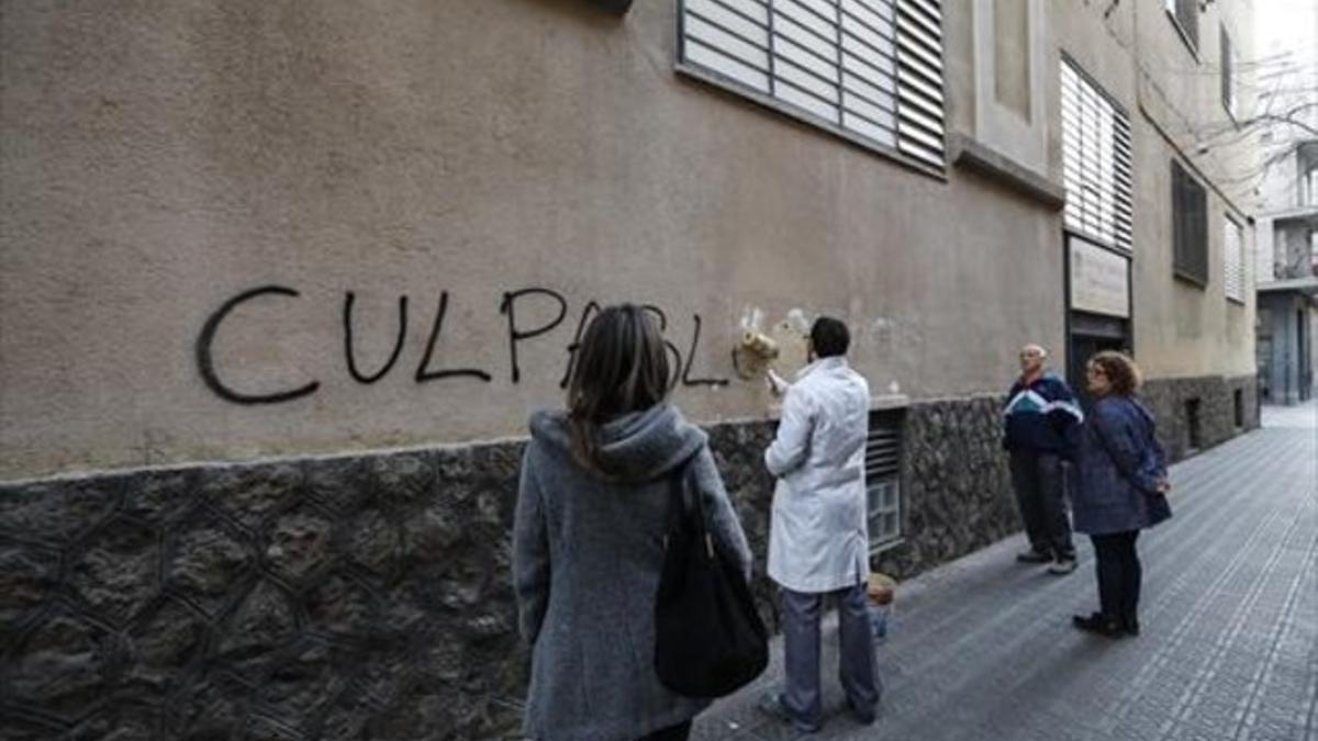 Un empleado de los Maristas Sants-Les Corts 'borra' una pintada en la fachada del centro.