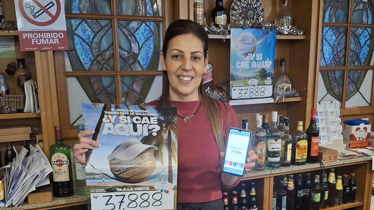 Nati Campos, con el número que juega su bar el día 22 y mostrando el móvil con la publicación del alcalde comunicando que 37.888 son los ciudadanos que tiene Vilagarcía.