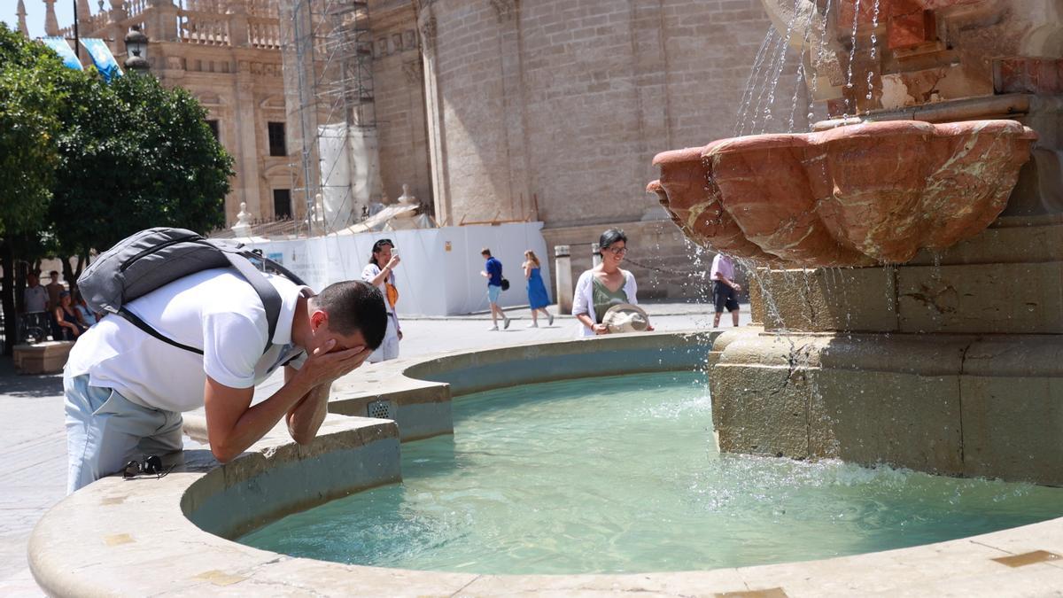 Un joven se refresca en una fuente para soportar las altas temperaturas.