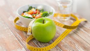 Dieta, adelgazamiento, manzana, cinta mÃ©trica, comida, desayuno. Adelgazar comiendo una dieta saludable y pesar concepto de la pÃ©rdida de cerca de manzana verde cinta y ensalada de mediciÃ³nhealthy eating, dieting, slimming and weigh loss concept - close up of green apple, measuring tape and salad. FUENTE: 123RF
