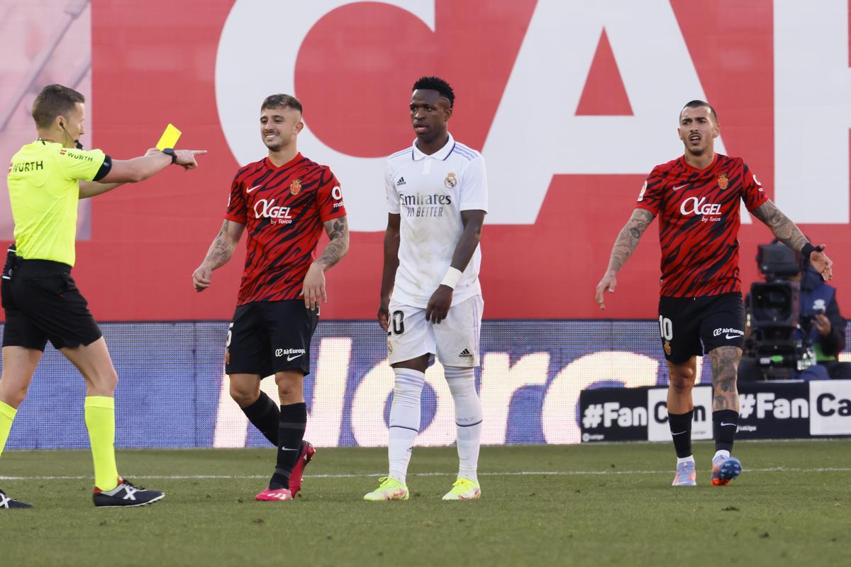 El árbitro Alejandro Hernández Hernández (i) muestra tarjeta amarilla al defensa del Real Mallorca Pablo Maffeo (2i) en presencia de Vinicius Jr (c)en foto de archivo de CATI CLADERA. EFE