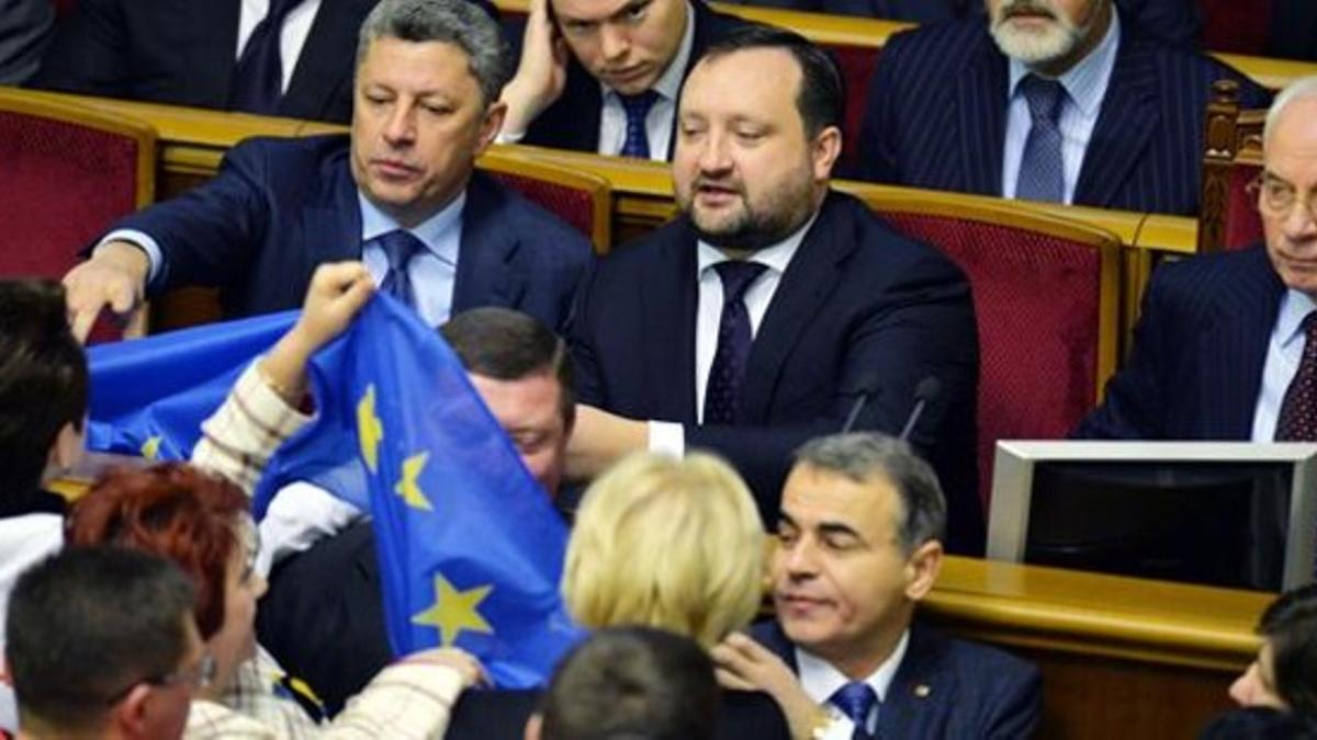 Diputados opositores esgrimen una bandera europea ante Azárov (derecha) y sus ministros en la Rada, este viernes en Kiev.