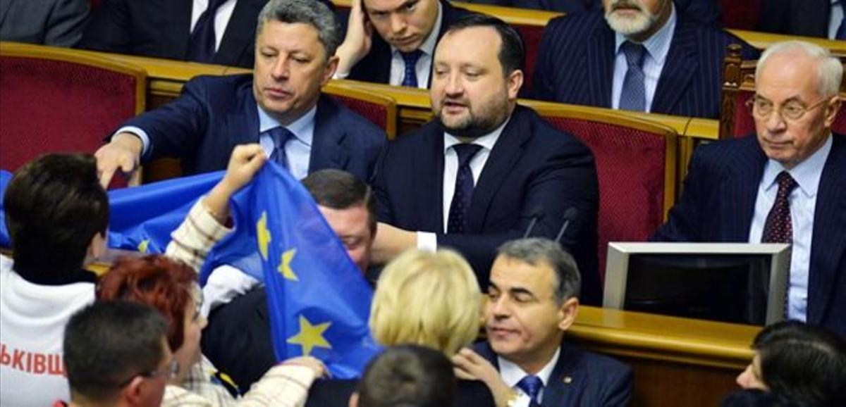 Diputats opositors esgrimeixen una bandera europea davant d’Azàrov (dreta) i els seus ministres a la Rada, aquest divendres a Kíev.