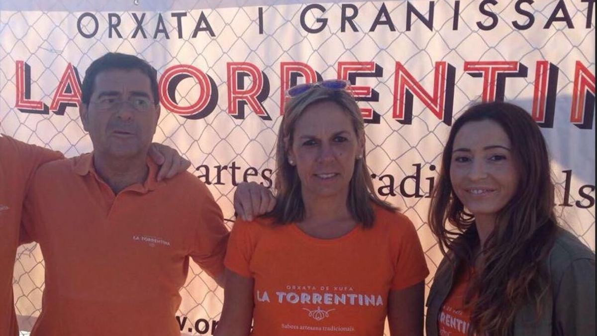 Evarist con su mujer y su hija, delante de un cartel de su negocio