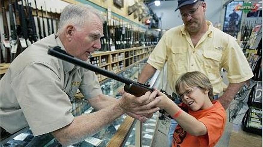 Un vendedor de armas ayuda a un niño a apuntar con un rifle en Fort Worth (Texas).