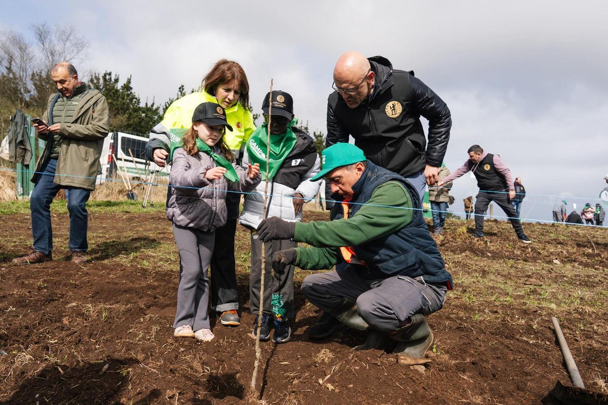 Dos niños plantando uno de los árboles con la ayuda de los miembros del proyecto.