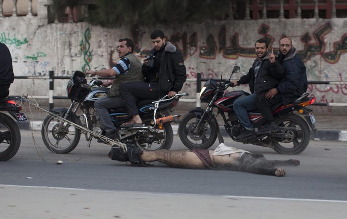 Militants palestins armats arrosseguen des d’una moto el cos d’un suposat col·laboracionista a qui han assassinat, dimarts a Gaza. Militants palestins armats arrosseguen des d’una moto el cos d’un suposat col·laboracionista a qui han assassinat, dimarts a Gaza.