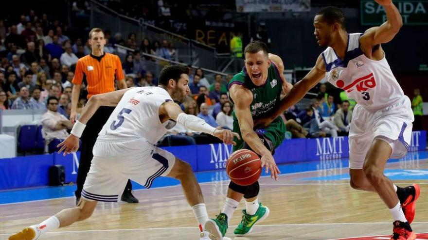 Nedovic, del Unicaja, intenta superar la defensa de Rudy Fernández y Randolph, del Real Madrid.