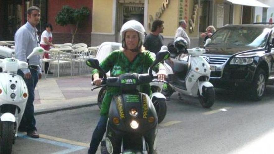 La concejala Adela Martínez-Cachá, conduciendo una moto eléctrica.