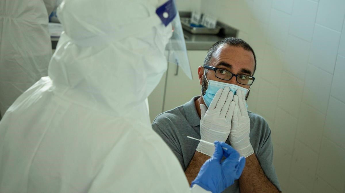 Un profesional sanitario se dispone a hacer una prueba PCR a un hombre.