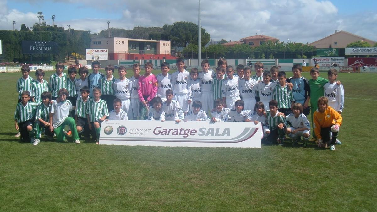 Álvarez, a sobre la lletra L del cartell publicitari, en la foto de família entre Madrid i el Betis a Peralada