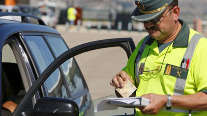 Un guardia civil pone una multa a un coche por superar la velocidad permitida.
