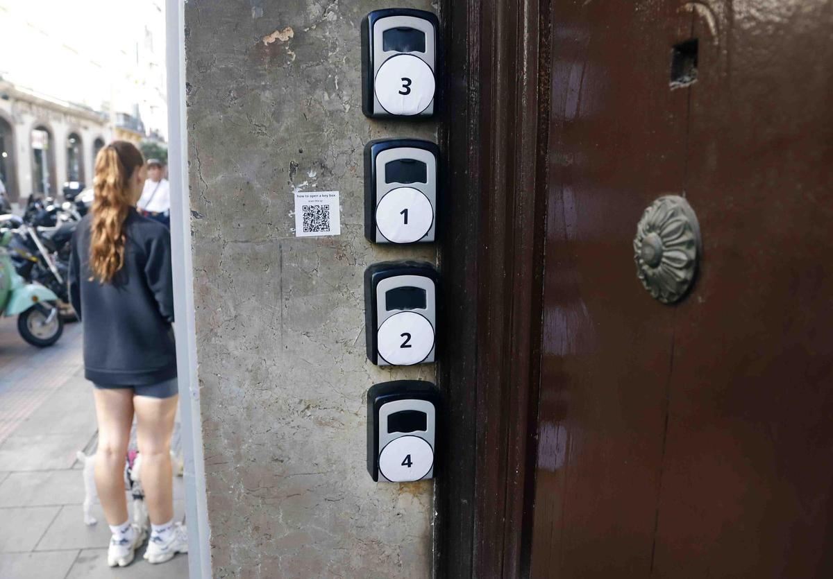 MLG 11-11-2024.-Varios turistas pasan cerca de cajas o cajetillas donde guardan las llaves los pisos turísticos que hay en el casco histórico de Málaga