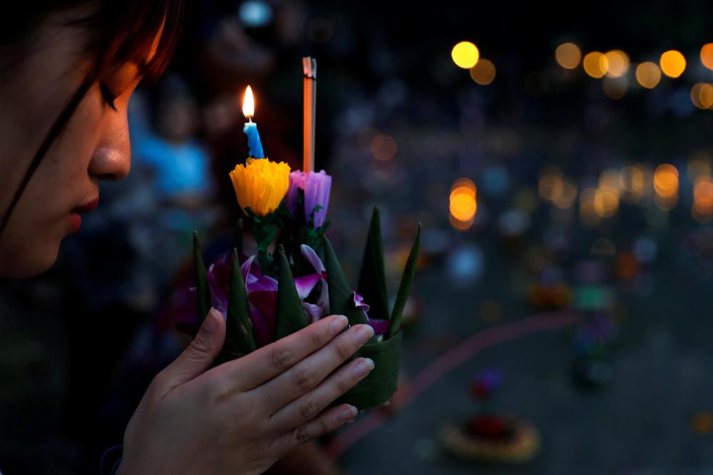 A girl prays before casting a krathong into a ...