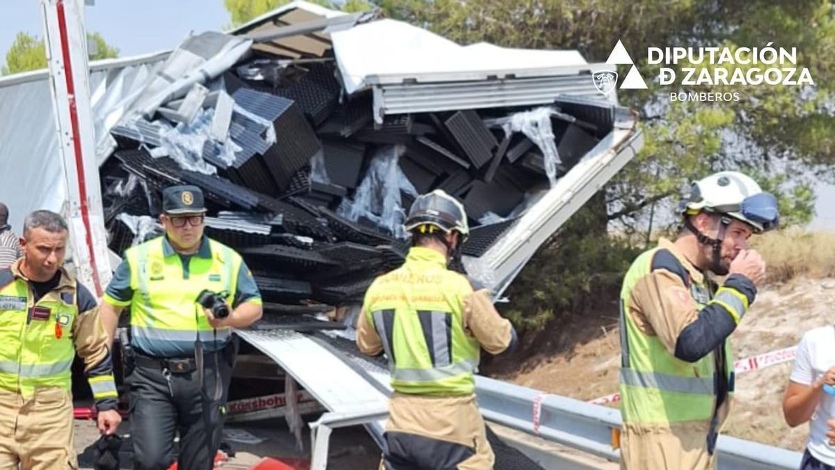 Efectivos de los bomberos de la Diputación de Zaragoza y de la Guardia Civil intervienen en el accidente registrado este sábado en la AP-2, a la altura de La Almolda.