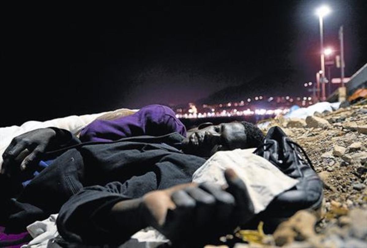 Un immigrant africà dorm a terra, sobre unes pedres, a prop del mar a Ventimiglia, ahir.