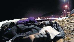 Un immigrant africà dorm a terra, sobre unes pedres, a prop del mar a Ventimiglia, ahir.