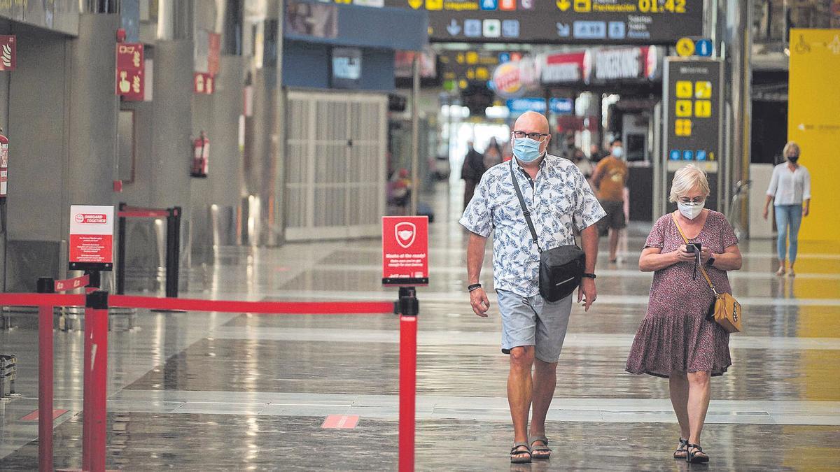 Dos turistas caminan por los pasillos de la terminal del Aeropuerto Tenerife Sur.