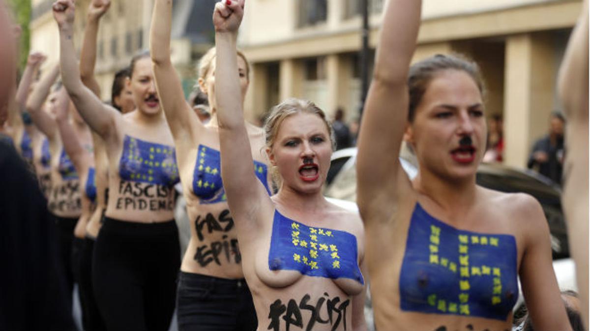 Las activistas desfilan por las calles de París con esvásticas y la bandera de la UE pintadas en el pecho.