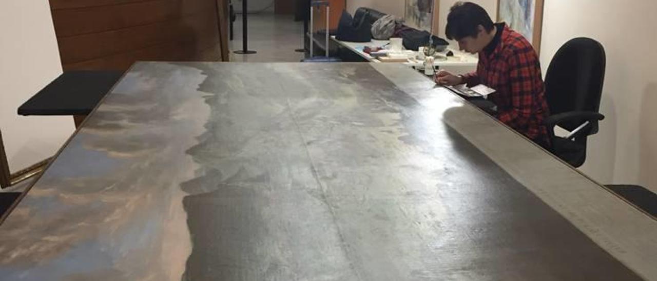Una experta repara el cuadro de la batalla de Almansa dañado, ayer en una sala de las Corts.
