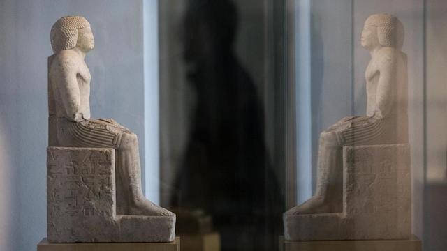 La estatua del sacerdote Gemefsetkap, recién adquirida para el Egipci, frente a su reflejo.