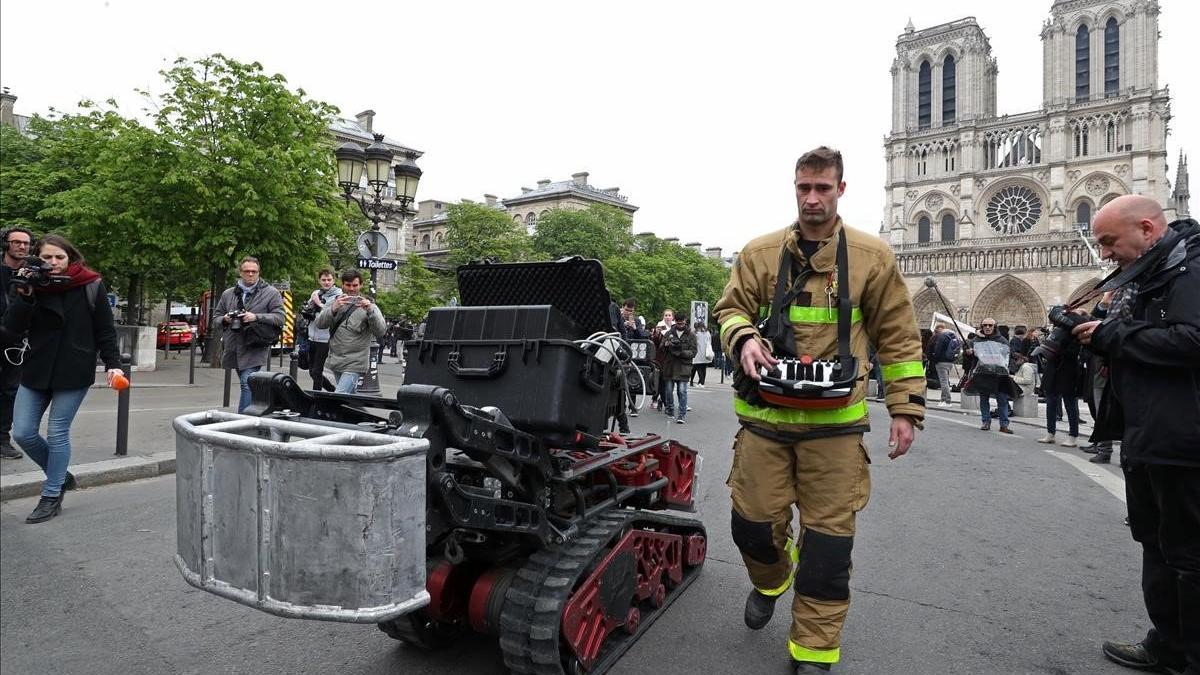 Un bombero, junto con el robot que ayudó a los bomberos en el incendio de Notre Dame, este martes.