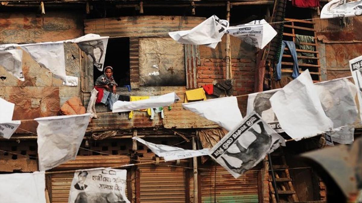 Vecinos del barrio de Shanty, Bangladesh, rodeados de publicidad electoral.