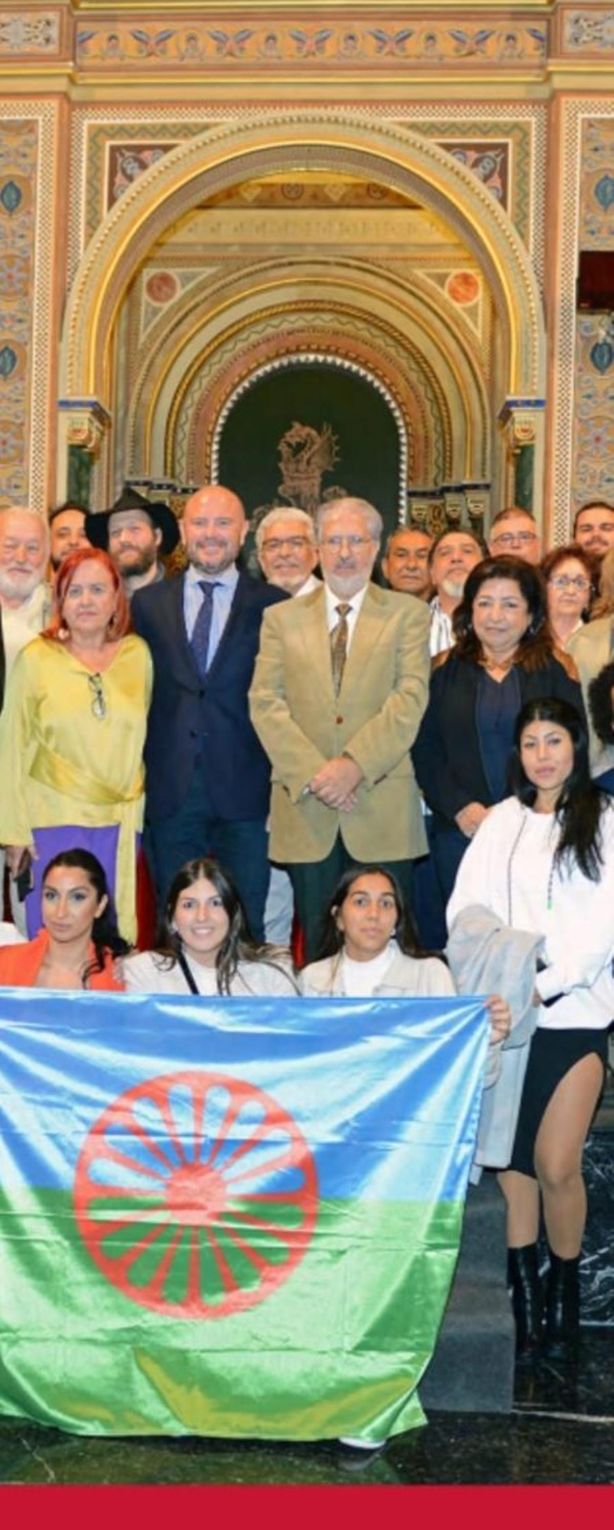 De pie y desde la izda.: Marga Pin, Antoni Francesc Gaspar, Diego Fernández y Alexandrina; detrás, gitanos europeos y sujetando la bandera, jóvenes gitanas de Arakerando Elda. III Congreso Internacional de Cultura Gitana, Valencia, 2022. | COLECCIÓN FAMILIAR