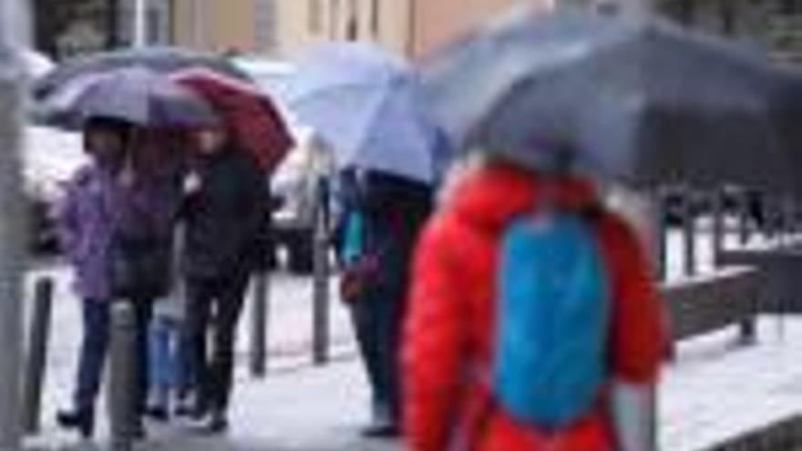 Un grup de vianants es protegia de la pluja amb paraigües ahir a la tarda a Girona.