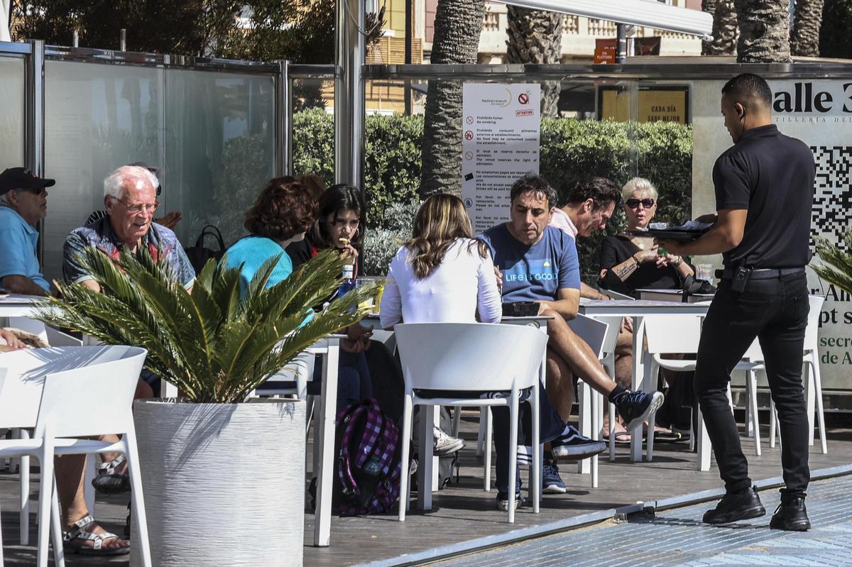 Un camarero atiende a los clientes de una terraza de Alicante.