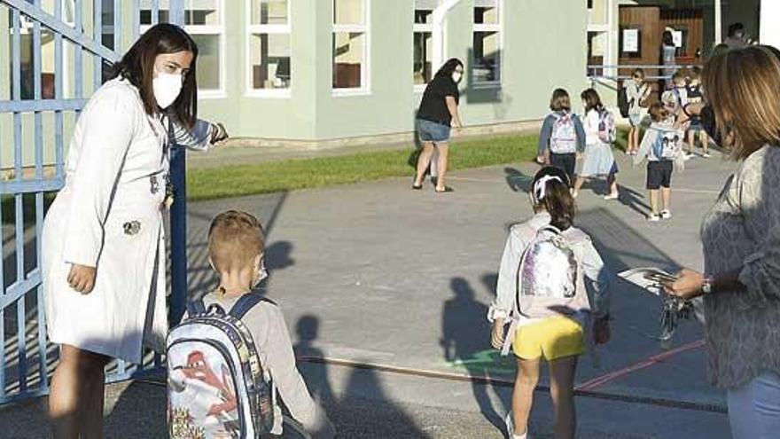 Una profesora señala el acceso a las aulas a niños en el CEIP Ponte dos Brozos de Arteixo.