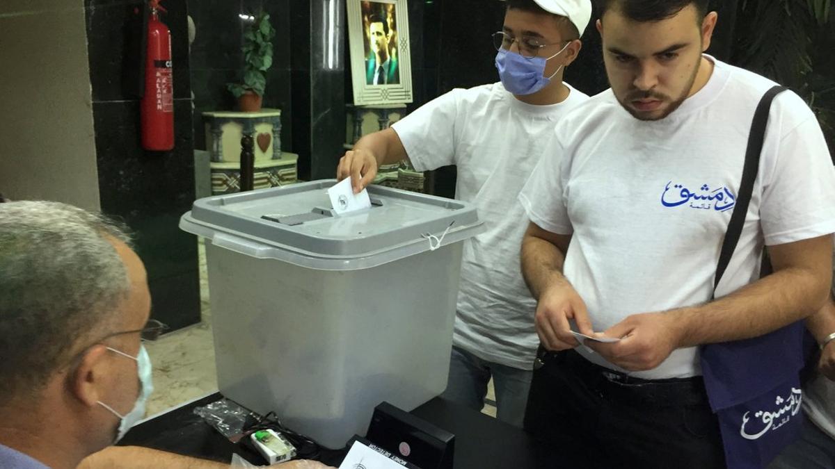 Dos hombres, en una mesa electoral, este domingo en Damasco.