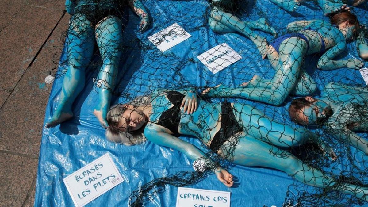 Activistas veganos con el cuerpo pintado de azul y dentro de redes de pesca, en Saint-Michel (París), el 20 de mayo.