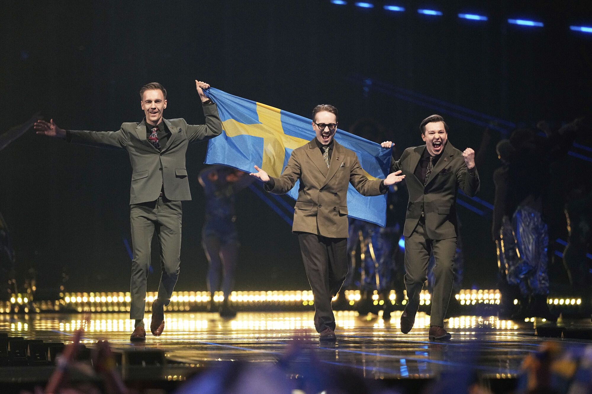 KAJ from Sweden walk onstage holding their countries flag during the Grand Final of the 69th Eurovision Song Contest, in Basel, Switzerland, Saturday, May 17, 2025. (AP Photo/Martin Meissner)