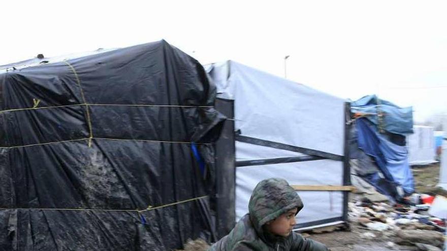 Un niño afgano mueve su bici en el barro de &quot;la jungla&quot; de Calais.  // Reuters