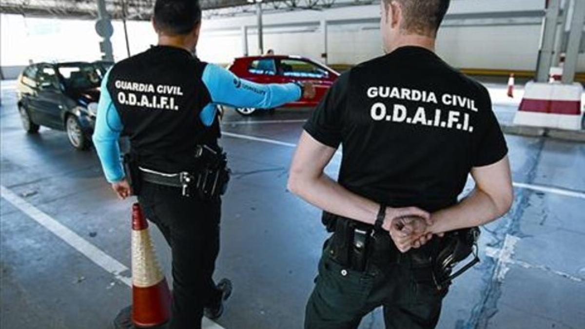 Dos guardias civiles paran un coche en la aduana de la Farga  de Moles.
